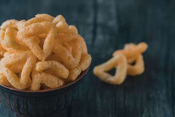 Crispy cornmeal snacks with cheese flavor in a brown bowl.