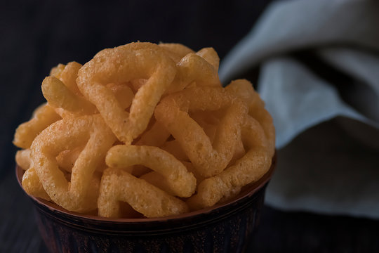 Crispy cornmeal snacks with cheese flavor in a brown bowl.