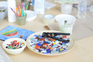 Process of making a mosaic picture from ceramic tile. The man organizes with a tweezers a puzzle of...