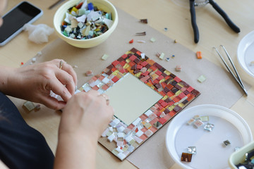 Process of making a mosaic picture from ceramic tile. The man organizes with a tweezers a puzzle of...