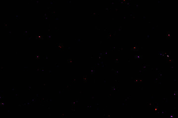 White blue red yellow green multi-colored highlights on black abstract background colored dust particles backlit from real flash multi-colored bokeh