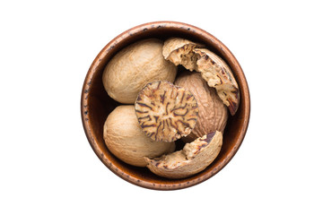 whole nutmeg spice in wooden bowl, isolated on white background. Seasoning top view