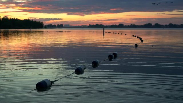 Summer sunrise over an empty swimming beach in Boyd Lake State Park in northern Colorado, static shot with geese flying