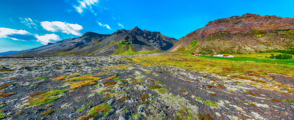 Typical view of Iceland  rocky lava plains, covered by moss and  mountains at background.
