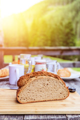 Rustic breakfast on an alpine hut: fresh crisp bread and milk in glass bottle, outdoors. Sunshine.