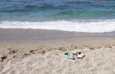Fototapeta na wymiar Mask, snorkel and beach Slippers on the sandy beach by the sea. Sea holidays in southern countries