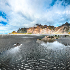 Dramatic sunny day and gorgeous rippled black sand beach  on Stokksnes cape in Iceland.