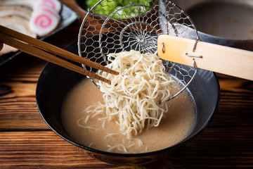 putting japanese ramen noodle in pork bone broth