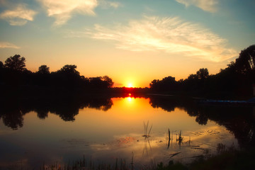 Natural summer river landscape. Sunset over the river. The sun is reflected in the water.