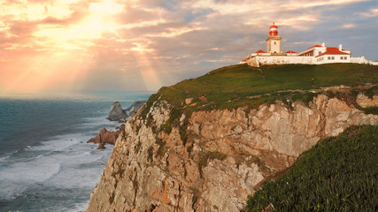 Fototapeta na wymiar Landscape, Cape Roca on a steep rock on the shores of the Atlantic Ocean at sunset and rays of the setting sun in Portugal