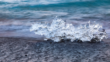 Fototapeta premium Incredible pieces of the iceberg sparkle on famous Diamond Beach at Jokulsarlon lagoon during sunset