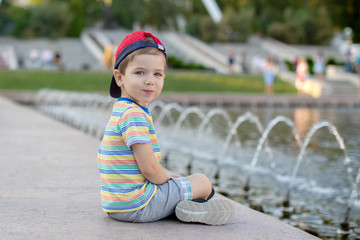 baby Boy sitting near the fountain in the city park