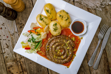 fried snail sausages with tomato sause and potatoes on the Board