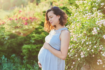 Beautiful pregnant woman relaxing in park future mom expecting child.