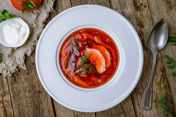 Borscht with sour cream on wooden table