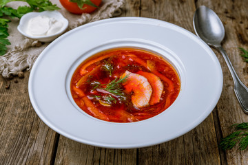 Borscht with sour cream on wooden table