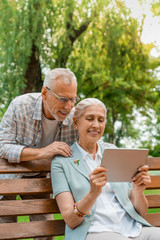 Vertical shot of happy smiling senior couple using digital tablet together