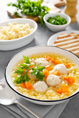 Hot chicken soup, broth with meatballs, carrot, pasta and fresh parsley