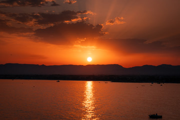 Sunset in Salou, Spain. It is a pleasant landscape where we see a sunset on the beach where the sun sets behind the mountain and the sea.