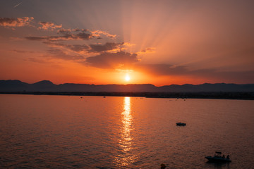 Sunset in Salou, Spain. It is a pleasant landscape where we see a sunset on the beach where the sun sets behind the mountain and the sea.
