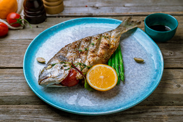 Dorado on grill at blue plate on old wooden table