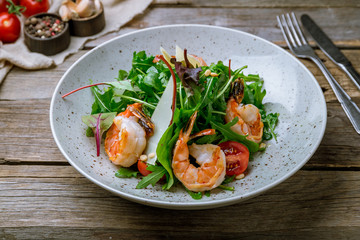 Arugula with shrimps and parmesan on old wooden table