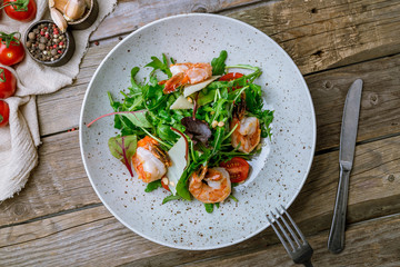 Arugula with shrimps and parmesan on old wooden table