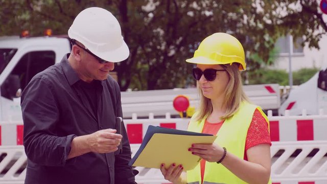 Construction site manager shaking female engineer's hand asking some questions about plans and office blueprints