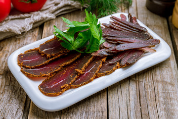 Dried sliced basturma on wooden table