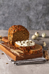Loaf of pumpkin bread on wooden cutting board. Slice of bread with cream cheese.