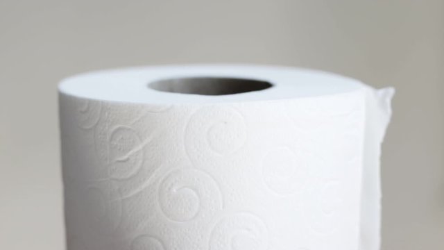 Toilet roll rotating slowly against a plain background
