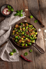 Roasted brussels sprouts with bacon in pan on wooden background. Rustic. Top view