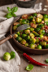 Roasted brussels sprouts with bacon in pan on wooden background. Rustic