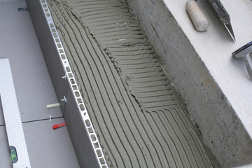 Tiler hands working on a new house entrance, local and professional handyman applying tiles to the steps.