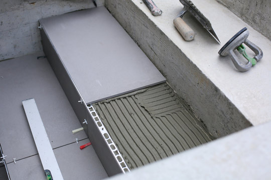 Tiler hands working on a new house entrance, local and professional handyman applying tiles to the steps.
