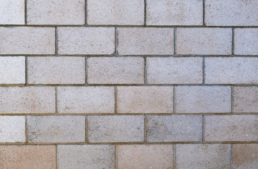Old white and tan layered concrete brick wall texture.