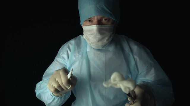 Surgeon leans towards the patient before surgery, first person view. Doctor with scalpel, grasper or forcep is ready to start cut a patient's tissues in hospital.