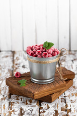 Frozen raspberries in a backet on wooden background.