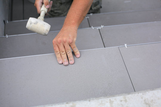 Tiler hands working on a new house entrance, local and professional handyman applying tiles to the steps.