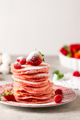 Stack of pink pancakes with strawberry. Pink colourful pancakes with berries. Breakfast