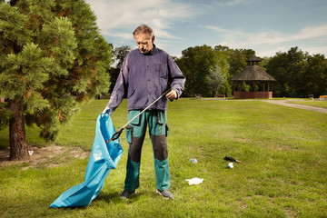Man in public service cleaning up trash in city park © Couperfield