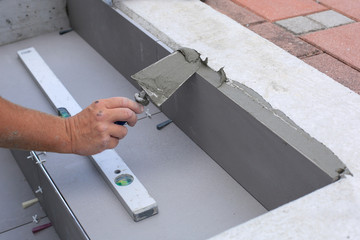 Tiler hands working on a new house entrance, local and professional handyman applying tiles to the steps.