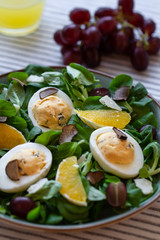 Green salad with eggs, oranges, parmesan and black truffles. Salad with truffles.