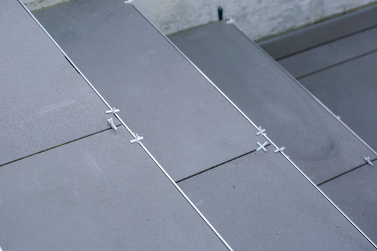 Tiler hands working on a new house entrance, local and professional handyman applying tiles to the steps.