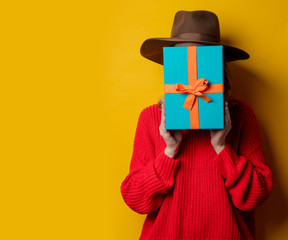 Young surprised woman in red sweater with gift box