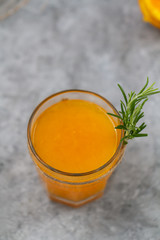 Glass of freshly pressed orange juice with orange squeezed halves on the table