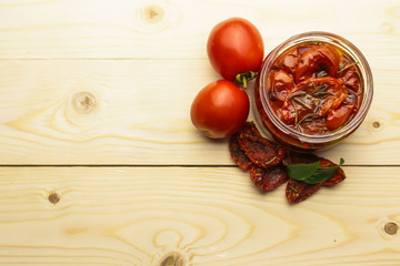 Glass jar with sun dried tomatoes on wooden table