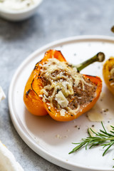 Stuffed paprika with meat, quinoa and cheese on a plate. Baked stuffed yellow orange peppers.