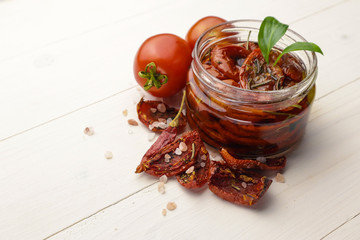 Glass jar with sun dried tomatoes on wooden table