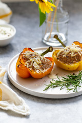 Stuffed paprika with meat, quinoa and cheese on a plate. Baked stuffed yellow orange peppers.